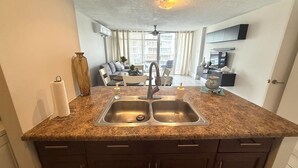A kitchen with a double sink, granite countertop, and dark cabinetry. - CB171- Beautiful Ocean View With One Bedroom (Carolina)