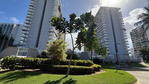 A residential building complex with multiple high-rise apartments, a well-maintained lawn, and a few palm trees. - CB171- Beautiful Ocean View With One Bedroom (Carolina)
