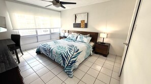 A bedroom with a bed, bedside tables, a desk, and a chair.