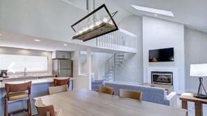 Una cocina amplia con comedor, una escalera y un televisor montado en la pared.