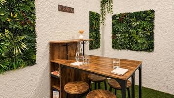 A wooden table with stools, a bar sign, and green wall decorations.