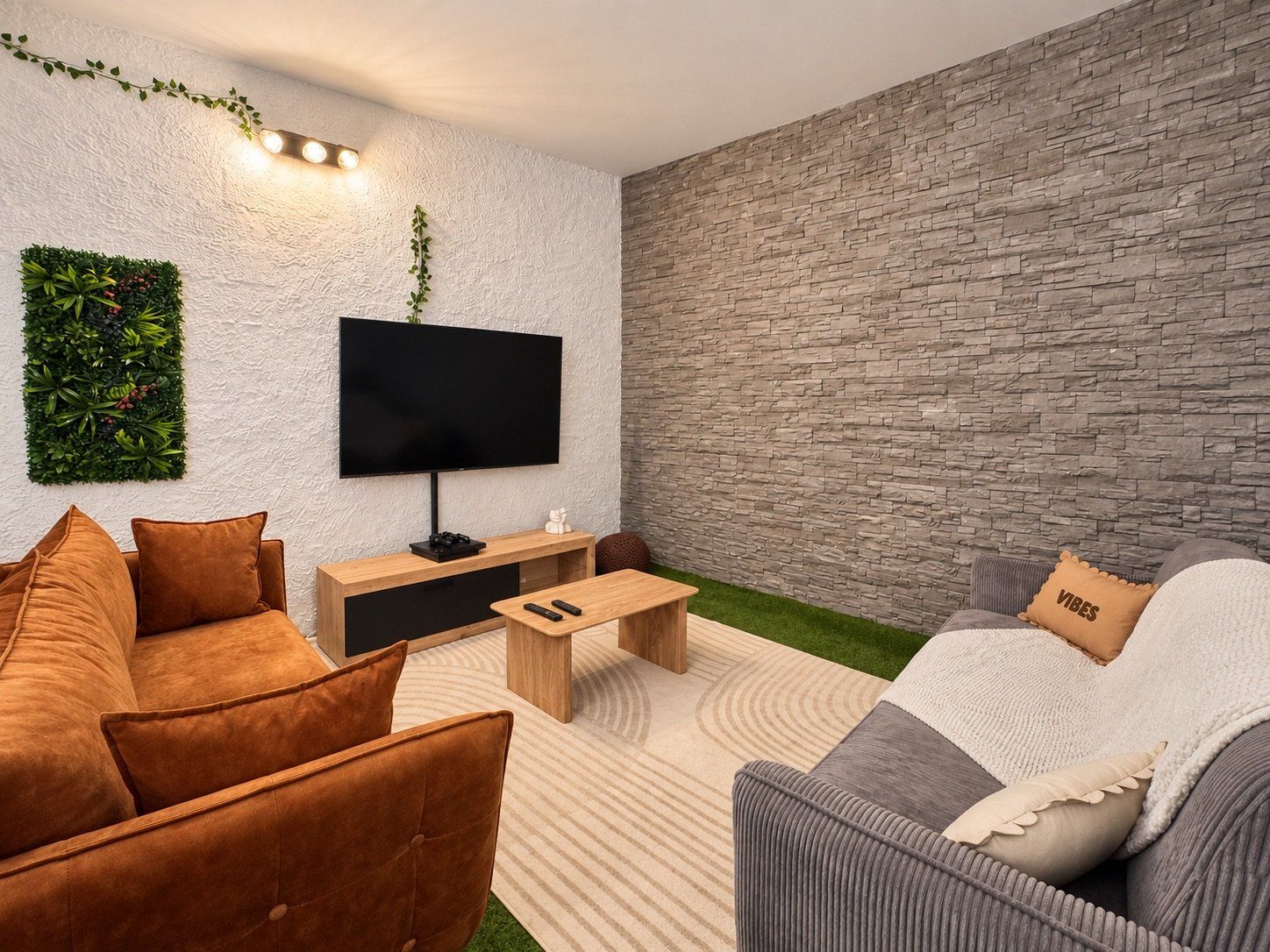 A modern living room with a flat-screen TV, a wooden coffee table, and two sofas.