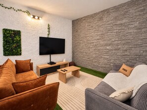 Een moderne woonkamer met een flatscreen televisie, een houten salontafel en twee banken.
