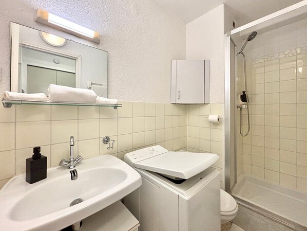 Un baño con lavamanos, espejo, toallero, mueble y ducha.
