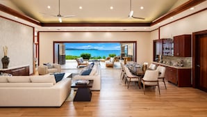Amplia sala de estar con sofá, mesa de comedor y sillas, una cocina con armarios de madera, y vista al mar.