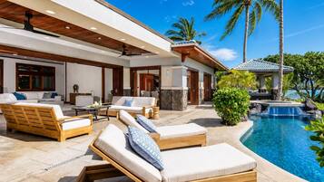 A modern outdoor pool area with lounge chairs, a stone structure, and a clear blue sky.