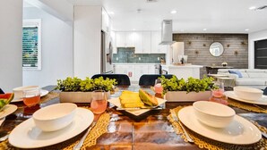 Una cocina moderna con armarios blancos, una isla central y un comedor con una mesa dispuesta para cuatro.