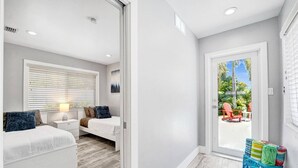 Un dormitorio moderno con cama, mesita de noche y ventana con persianas.
