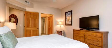 Un dormitorio con cama, cómoda de madera, televisor y ventilador de techo.