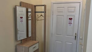 Un couloir avec une coiffeuse en bois, un miroir et une porte sur laquelle est accroché un porte-manteau.