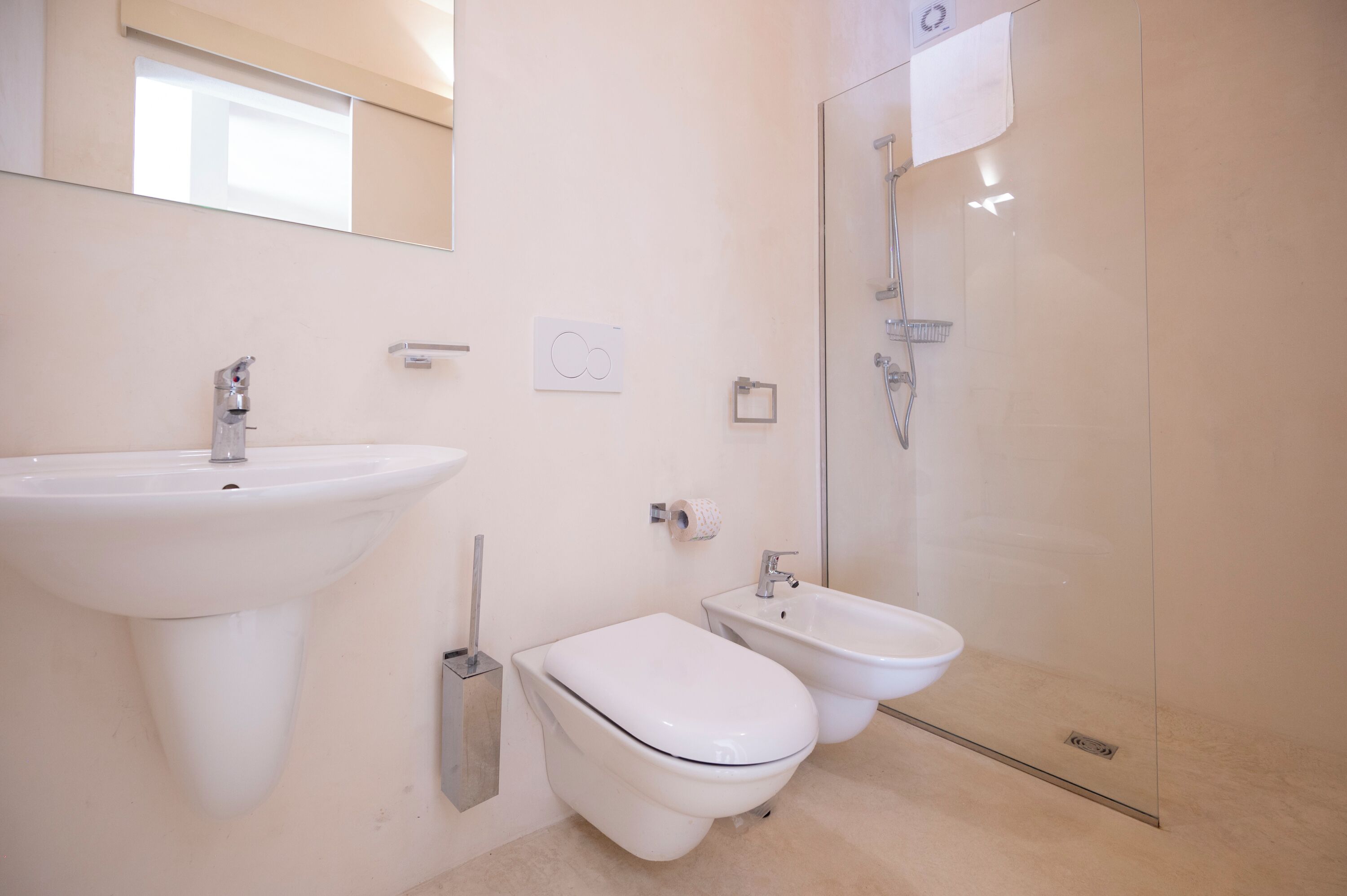 A modern bathroom with a sink, bidet, toilet, and glass shower enclosure.