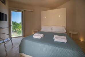 A bedroom with a large bed, two bedside tables, a chair, and a TV mounted on the wall. - Sky Dream Oasi Vendicari Noto (Noto)