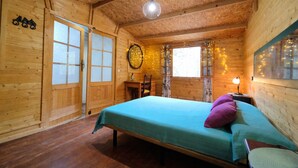 Habitación de cabaña de madera con una cama, un escritorio y una ventana con cortinas.