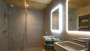 Une salle de bain moderne avec une douche, un lavabo et un miroir.