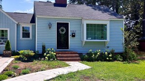 A single-story house with a front door, a small porch, and a garage. - Bayview Bungalow-Cozy Stay Near Downtown (Fayetteville)