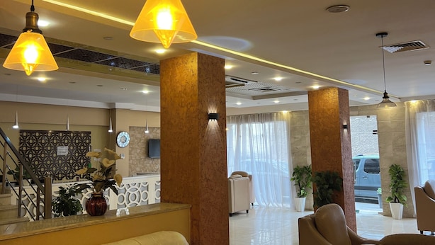 A hotel lobby with a reception desk, seating area, and a staircase. - Hôtel kassar  (Oran)