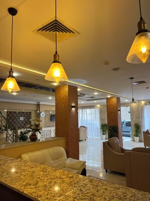 A hotel lobby with a reception desk, seating area, and a staircase. - Hôtel kassar  (Oran)