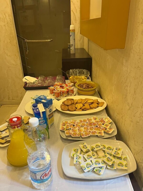 A buffet table with various food items, including pastries, cookies, and packaged snacks. - Hôtel kassar (Oran)