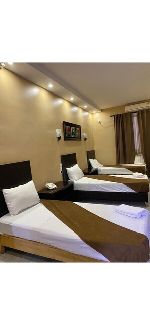 A hotel room with two single beds, a bedside table with a phone, and a wall-mounted artwork. - Hôtel kassar  (Oran)