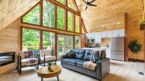 Une cabane en bois spacieuse, dotée d’un grand salon, d’une cuisine et d’une cheminée.