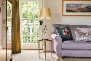 Une pièce avec un canapé, une lampe, une fenêtre et une porte.