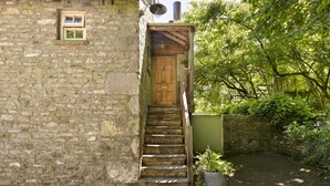 A stone building with a wooden staircase leading to a door. - The Room Rawsons in Levens (Kendal)