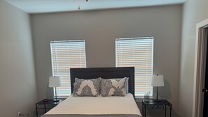 A bedroom with a bed, two bedside tables with lamps, and two windows with blinds. - 2-bedroom apartment in lovely Victoria with WiFi, AC (Victoria)