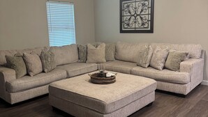 A living room with a sectional sofa, a coffee table, a ceiling fan, and a window with blinds. - 2-bedroom apartment in lovely Victoria with WiFi, AC (Victoria)