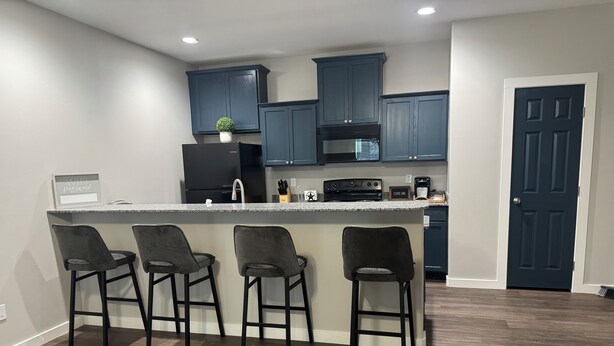 A modern kitchen with dark blue cabinets, a granite countertop, and four bar stools. - 2-bedroom apartment in lovely Victoria with WiFi, AC (Victoria)