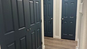 A hallway with three dark wooden doors, a light-colored wall, and a wooden floor. - 2-bedroom apartment in lovely Victoria with WiFi, AC (Victoria)