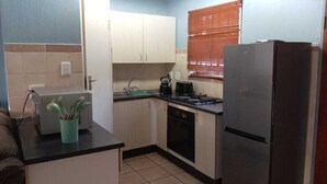 A compact kitchen with a refrigerator, stove, sink, and cabinets. - Secure, Spacious & Fully Equipped – Your Ideal Townhouse Stay 4 (Pretoria)