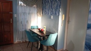 A dining area with a table and chairs, a telephone, and a door. - Secure, Spacious & Fully Equipped – Your Ideal Townhouse Stay 4 (Pretoria)