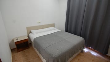 Ein Schlafzimmer mit einem Bett, einem Nachttisch und einem Vorhang.