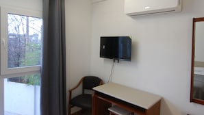 A room with a desk, chair, window with curtains, and an air conditioning unit. - Hostal El 36 (Sesena)
