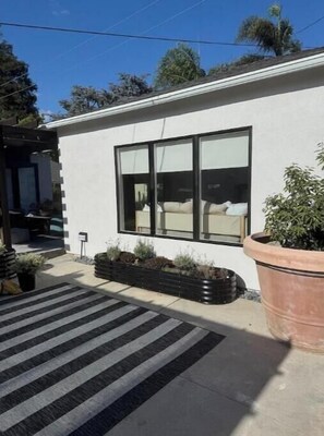Un bâtiment moderne doté de grandes fenêtres, d’un tapis rayé noir et blanc et d’un grand bac à plantes.