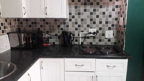 Una cocina con gabinetes blancos, encimera negra y salpicadero de azulejos.