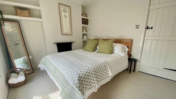 A bedroom with a bed, a mirror, a bedside table, and a wardrobe. - Morfach Charming Modern Cottage within Conwy walls (Morfach)