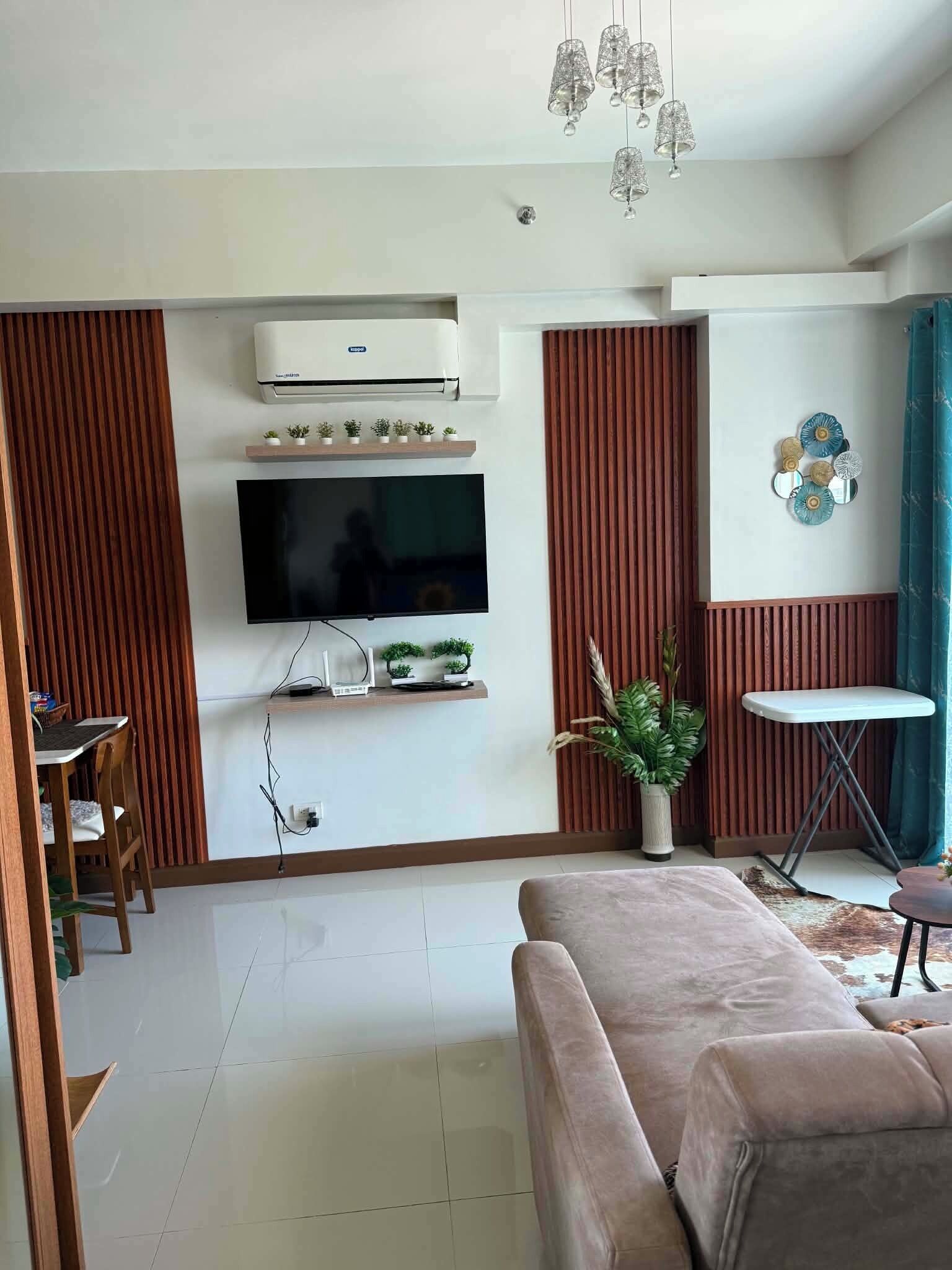 Un salon moderne doté d’un téléviseur à écran plat, d’un canapé, d’un coin repas avec des chaises et d’une petite table.