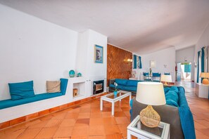 Uma sala de estar com sofá, mesa de centro, lareira e parede com padrão em herringbone.