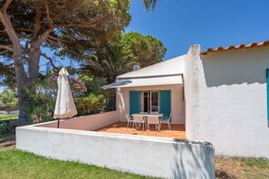 A white building with a patio, a table with chairs, and a white umbrella. - Ocean Villa – Holiday Home with Sea View and Shared Pool (Prainha)