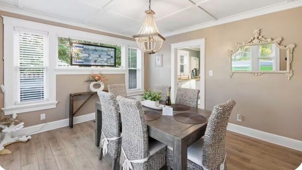 A dining room with a wooden table, wicker chairs, a chandelier, and a stained glass window. - Happy Place🏖️🐶 Prime Historic 1915 Pet-Friendly Home:Great Beach & Downtown Spot! (Wilmington)