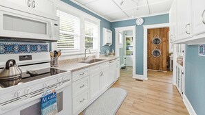 A kitchen with white cabinets, a stove, and a kettle. - Happy Place🏖️🐶 Prime Historic 1915 Pet-Friendly Home:Great Beach & Downtown Spot! (Wilmington)