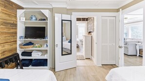 A hotel room with a bed, a wardrobe, a television, and a bathroom visible through an open door. - Happy Place🏖️🐶 Prime Historic 1915 Pet-Friendly Home:Great Beach & Downtown Spot! (Wilmington)