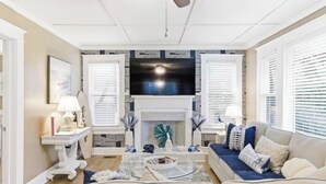 A living room with a fireplace, a sofa, a coffee table, and a television. - Happy Place🏖️🐶 Prime Historic 1915 Pet-Friendly Home:Great Beach & Downtown Spot! (Wilmington)