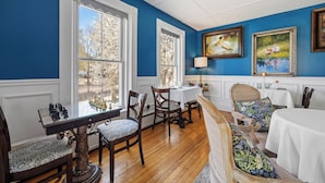 A dining room with a chessboard, wooden chairs, a table, and paintings on the wall.
