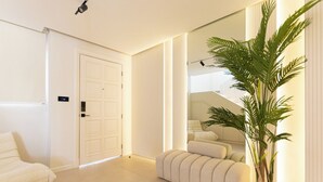 Een moderne hotelkamer met een grote spiegel, een kamerplant en een bank.