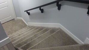 A carpeted staircase with a handrail, white walls, and a door. - Modern, well furnished 1 bedroom home with free street parking (Spruce Grove)