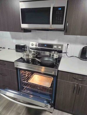 A kitchen with a stainless steel stove, oven, and microwave. - Modern, well furnished 1 bedroom home with free street parking (Spruce Grove)