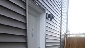 A house with a white door, a small porch with a blue step, and a wooden fence in the background. - Modern, well furnished 1 bedroom home with free street parking (Spruce Grove)
