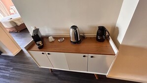 Un angolo cottura attrezzato con macchina da caffè, bollitore ed un tostapane su un piano di lavoro in legno.